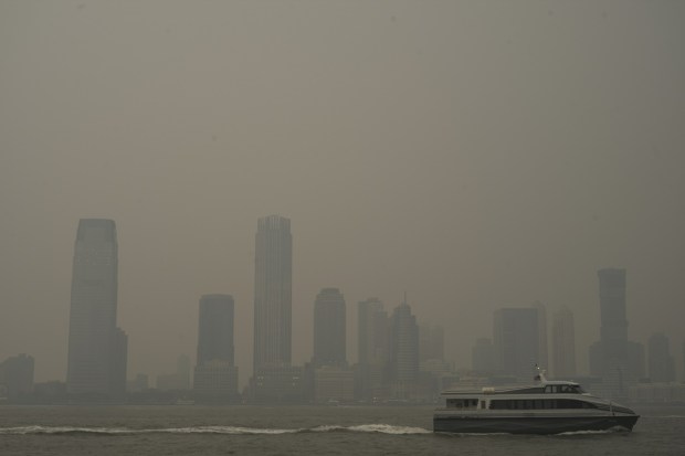 Buildings in Jersey City, N.J. are partially obscured by smoke from Canadian wildfires as a ferry travels up the Hudson River, seen from the Manhattan borough of New York. (Image: AP Photo/Patrick Sison)