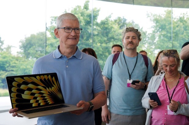 Apple CEO Tim Cook holds a new MacBook laptop at Apple's annual Worldwide Developers Conference at the company's headquarters in Cupertino, California on June 5, 2023. (Image: REUTERS)