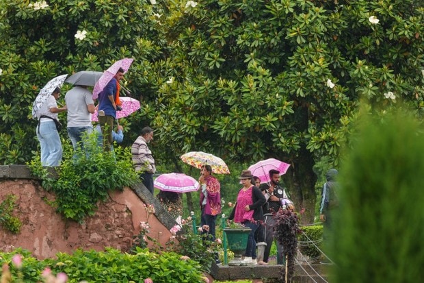 People enjoying the weather at Mughal Garden in Srinagar during rainfall on May 31, 2023. (Image: PTI)