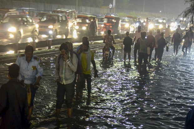 Commuters wade through the waterlogged Delhi-Gurugram expressway service road during rain in Gurugram on May 30, 2023. (Image: PTI)