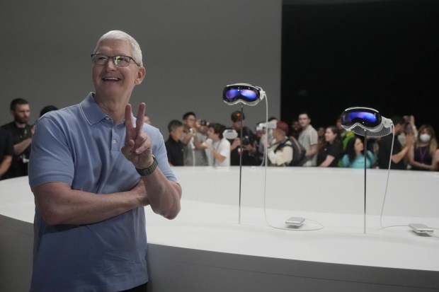 Apple CEO Tim Cook poses for photos in front of the company's new Apple Vision Pro headsets in a showroom on the Apple campus Monday, June 5, 2023, in Cupertino, Calif. (Image: AP)