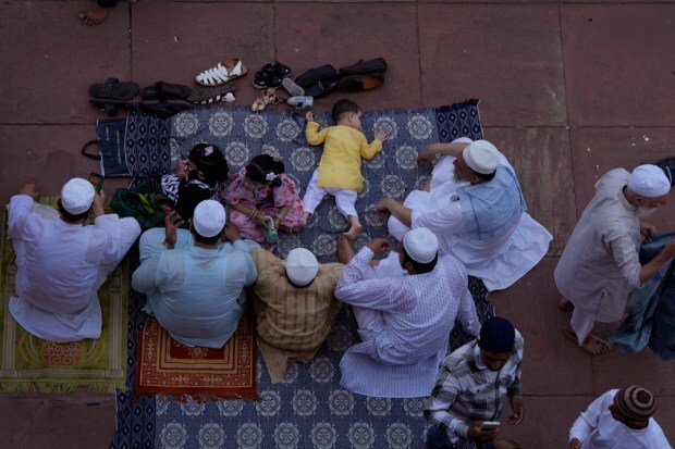 A family sits and talk after offering Eid al-Adha prayers at the Jama Masjid. (Image: AP)