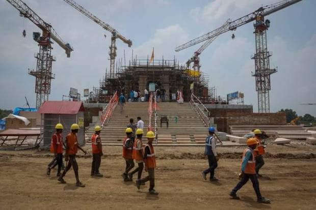 In Ayodhya, workers walk in front of the under construction Hindu Ram Temple. REUTERS