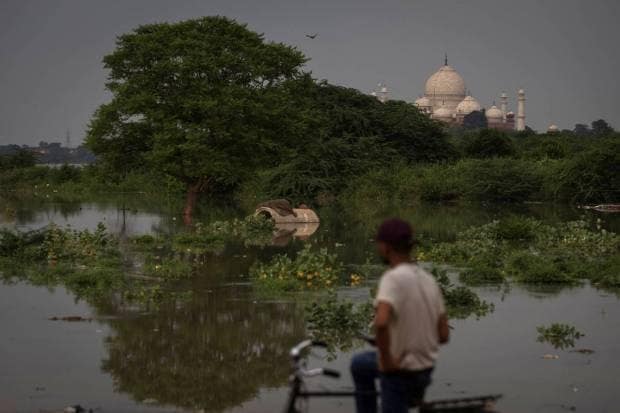 A man stands at a road side in front of the historic Taj Mahal as the Yamuna river overflows following heavy rains, in Agra. REUTERS