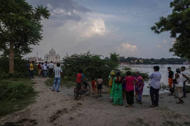 People stand next to the flood waters in front of the historic Taj Mahal as the Yamuna river overflows following heavy rains, in Agra. REUTERS