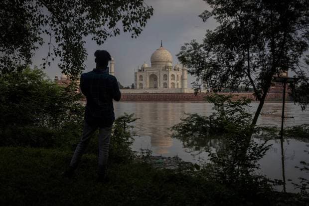 A man takes picture of historic Taj Mahal as the Yamuna river overflows following heavy rains, in Agra. REUTERS