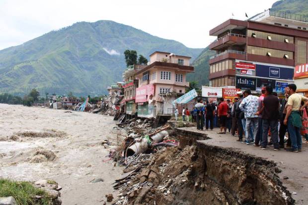 People stand by a road washed away by the River Beas swollen due to heavy rains in Kullu District, Himachal Pradesh, India. (AP Photo)