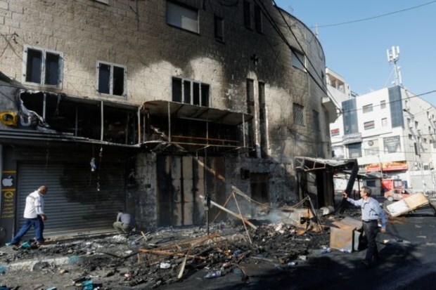 People walk past debris and a building damaged amid an Israeli military operation. (Image: Reuters)