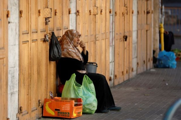 A Palestinian woman sits in front of closed shops during a general strike over an Israeli military operation in Jenin, in Hebron, in the Israeli-occupied West Bank July 4. (Image: Reuters)