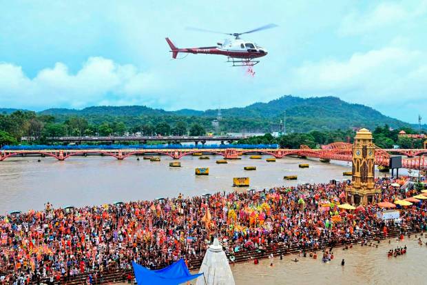 A helicopter showers flowers to the Lord Shiva devotees or Kanwariyas gathered at Har Ki Pauri Ghat to collect holy water from the Ganga river during 'Kanwar Yatra' in the holy month of Shravan, in Haridwar. (PTI Photo)(PTI07_06_2023_000246B)