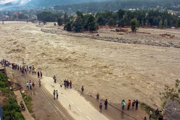 Locals walk along the eroded riverbank damaged by the swollen Beas river following heavy monsoon rains, in Kullu. (PTI Photo)