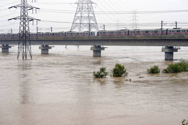 A Delhi Metro train moves slowly over the bridge spanning the swollen Yamuna river, in New Delhi. (PTI)