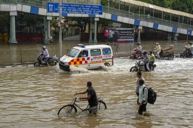 People wade through a waterlogged road at ITO as the Yamuna river floods nearby areas, in New Delhi.(PTI Photo)