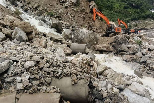 A backhoe machine clears the debris from a road after heavy rains near Lambagad, in Chamoli. (PTI Photo)