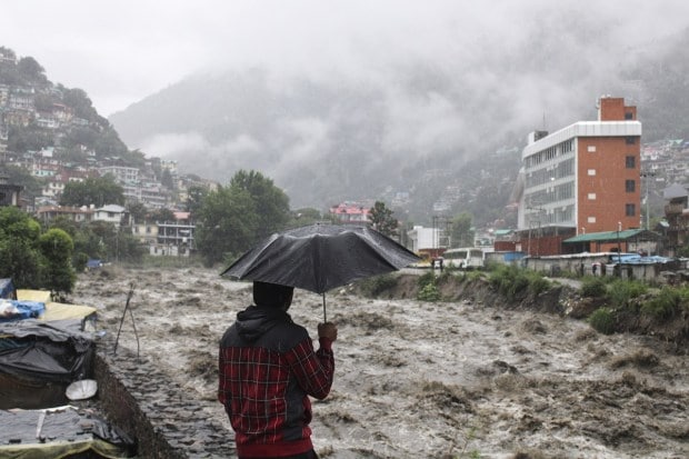 A man looks at a swollen River Beas following heavy rains in Kullu, Himachal Pradesh, India on July 9, 2023. (Image: AP Photo/ Aqil Khan)