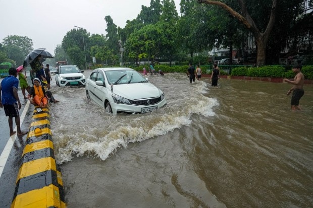 Vehicles make their way on a waterlogged road after heavy monsoon rains, at South Avenue in New Delhi. (Image: PTI Photo/Kamal Singh)