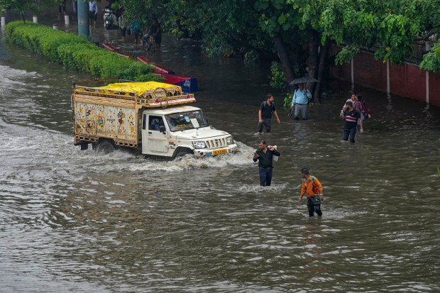 People wade through a waterlogged road following heavy monsoon rains. (Image: PTI Photo/Manvernder Vashist Lav)