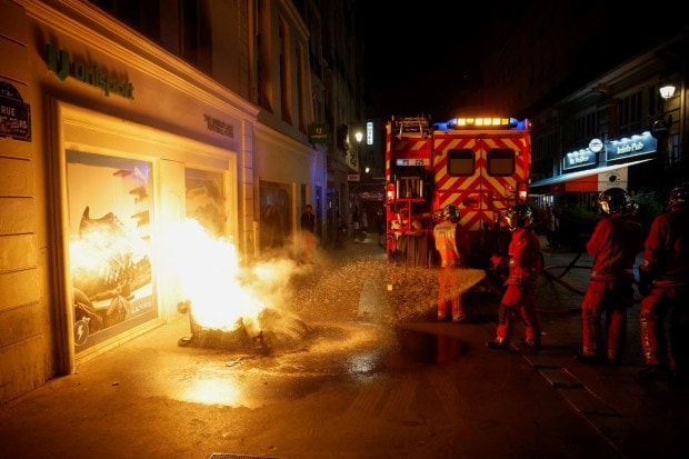 Firefighters work to extinguish a burning container as unrest continues following the death of Nahel, a 17-year-old teenager killed by a French police officer in Nanterre during a traffic stop, and against police violence, in Paris, France. (Image: Reuters/Juan Medina)