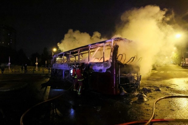 Firefighters use a water hose on a burnt bus as unrest continues following the death of a 17-year-old teenager killed by a French police officer during a traffic stop, in Nanterre, Paris suburb. (Image: REUTERS/Yves Herman)