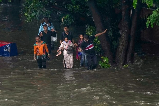 People wade through a waterlogged road following heavy monsoon rains. (Image: PTI Photo/Manvernder Vashist Lav)
