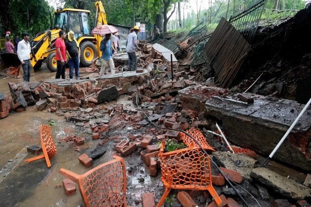 Locals and officials near a collapsed wall after monsoon rain at Sundar Nagar in New Delhi. (Image: PTI Photo/Kamal Singh)