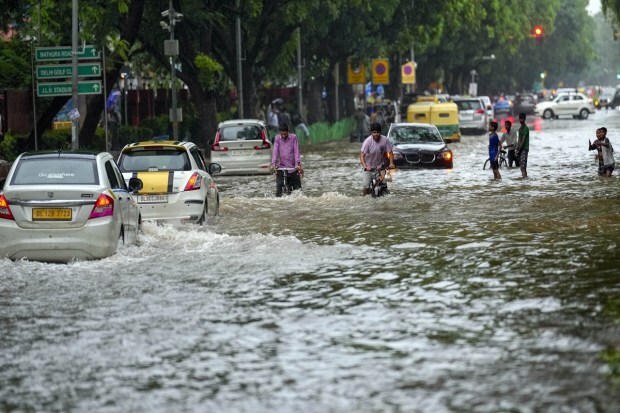 Commuters move through a waterlogged road at Rabindra Nagar after monsoon rain in New Delhi. (Image: PTI Photo/Kamal Singh)