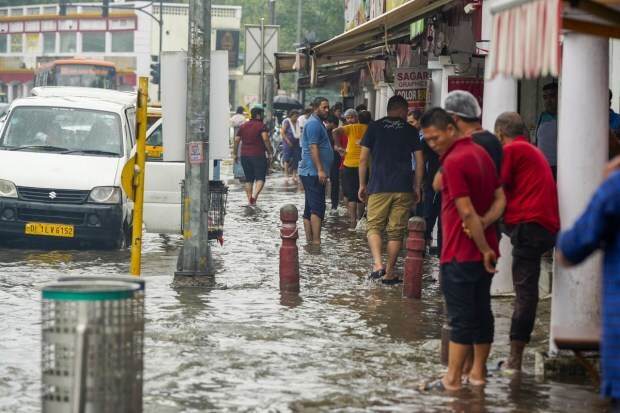 Commuters pass through a waterlogged street amid monsoon rains, in New Delhi. (Image: PTI Photo/Atul Yadav)