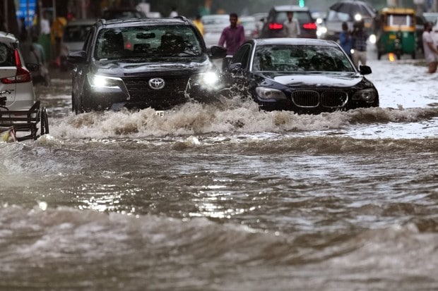 Commuters finding it difficult to move through a waterlogged road at Rabindra Nagar after monsoon rain in New Delhi. (Image: PTI Photo/Kamal Singh)