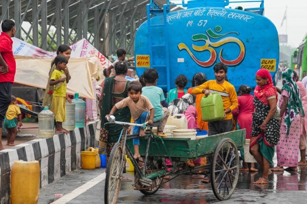 People from low-lying areas around the Yamuna river collect drinking water near their makeshift tents along a road on July 11. (Image: PTI)