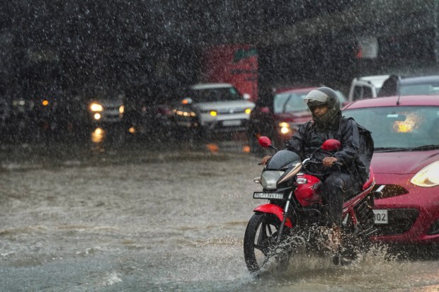 People commute through a waterlogged road amid monsoon rains in New Delhi on July 6. (Image: PTI)