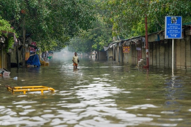 A man wades through a waterlogged road as the swollen Yamuna river inundates nearby areas, at ITO in New Delhi on July 15, 2023. (Image: PTI Photo/Manvender Vashist Lav)