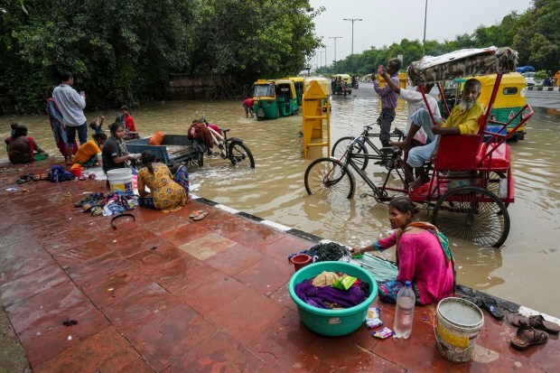 Locals wash clothes in floodwater near Shanti Van as the swollen Yamuna river inundates nearby areas, in New Delhi on July 15, 2023. (Image: PTI Photo/Kamal Singh)