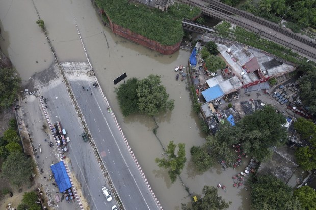 A road is inundated with water from the swollen river Yamuna in New Delhi on July 15, 2023. The water level of the Yamuna River flowing through the Indian capital topped a 40-year record and reached 207.71 meters (681.5 feet) on Wednesday evening, according to a statement by the office of New Delhi's top elected official, Arvind Kejriwal. Authorities have moved nearly 30,000 people to relief camps and also converted some schools into relief camps in the badly hit areas, the statement said. (Image: AP Photo/Piyush Nagpal)