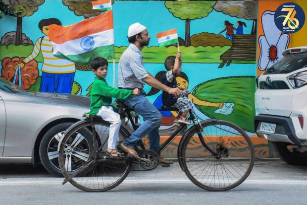 Locals ride past on the occasion of the 77th independence day, in Moradabad. (PTI Photo)