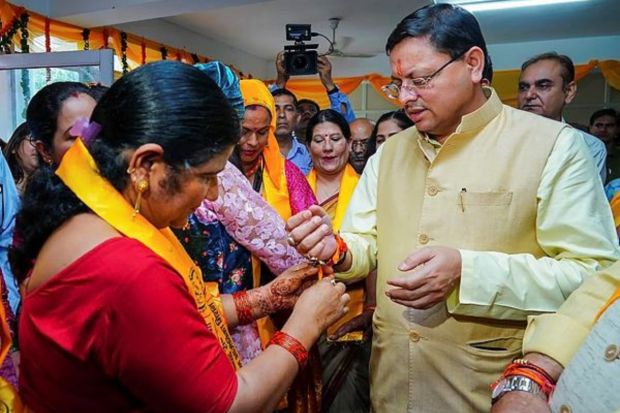 A woman ties a 'rakhi' on the wrist of Uttarakhand Chief Minister Pushkar Singh Dhami's wrist during his visit to 'rakhi' stalls set up by women self-help groups at Secretariat in Dehradun on Thursday. (PTI Photo)