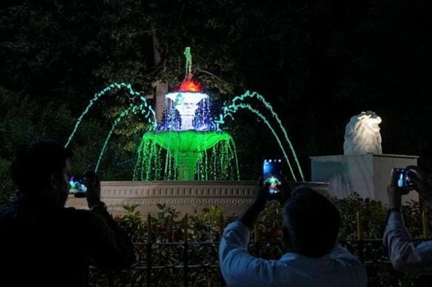 People look at a fountain illuminated in the Indian Tricolour during a review by Delhi Lt. Governor Vinai Kumar Saxena ahead of the G20 Summit in New Delhi. (PTI Photo/Kamal Singh)