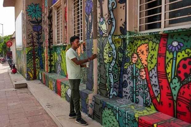 An artist paints graffiti at the Mandi House metro station ahead of the G20 Summit. (PTI Photo/Manvender Vashist Lav)