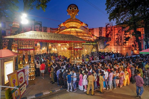 People wait in queue to enter a community Puja pandal on Saptami during Durga Puja festival in Kolkata. (PTI Photo)