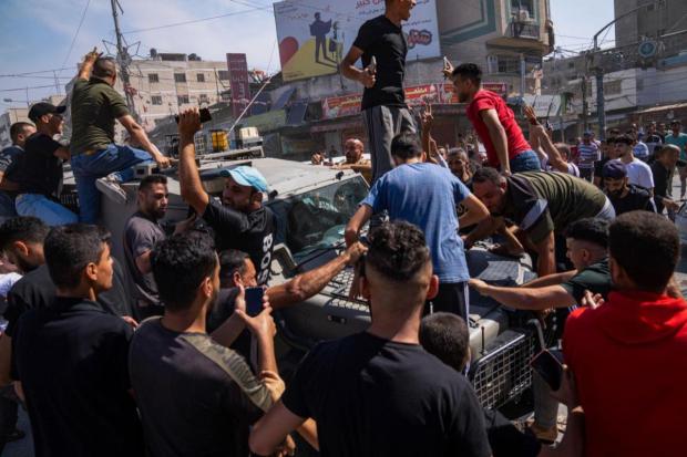 Palestinians gather around an Israeli army vehicle that Palestinian militants drove from Israel into Gaza, in Shejaiya, Gaza Strip, Saturday, October 7. The Hamas militant group, which has ruled the Strip since 2007, launched thousands of rockets on Saturday as it said it was beginning a major military operation against Israel. (Image/AP)