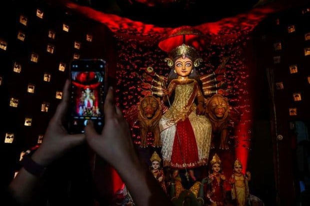 A devotee takes picture of an idol of Hindu goddess Durga at a temporary worship venue in the early hours of the final day of Durga Puja festival in Kolkata on October 24. (Image: AP)