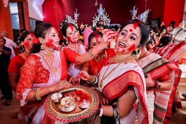 Women apply vermillion on each other as they participate in 'Sindoor Khela' on 'Vijayadashami' in Jaipur (Image: PTI)