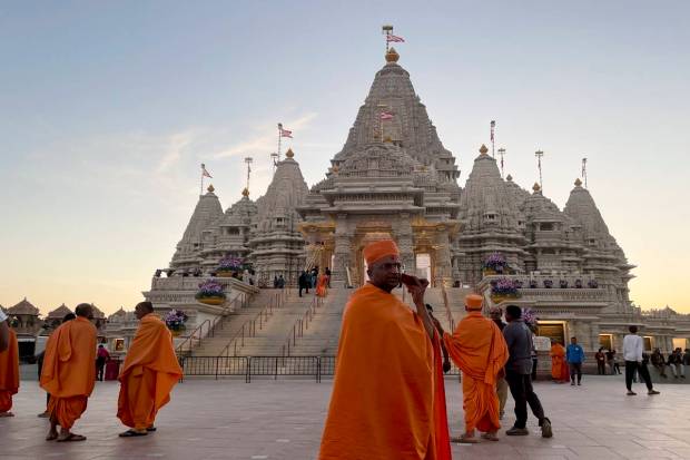 Monks in saffron robes walk in front of the BAPS Swaminarayan Akshardham. (AP Photo)