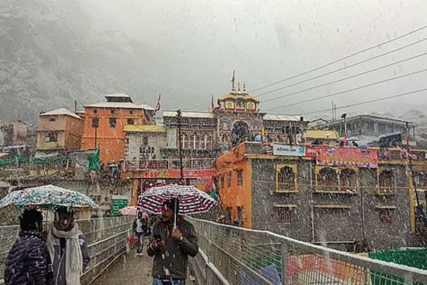 People at Badrinath Dham during snowfall, in Chamoli district. (PTI Photo)
