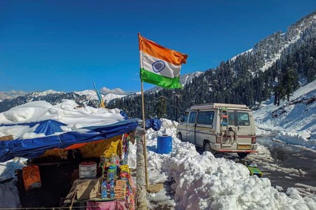 An Indian flag posted near a makeshift shop in a snow covered area in Bhaderwah. The tourism business has got a new lease of life following snowfall. (PTI Photo)
