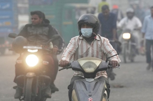 Commuters on a road amid low visibility due to smog in New Delhi onTuesday. (PTI Photo)