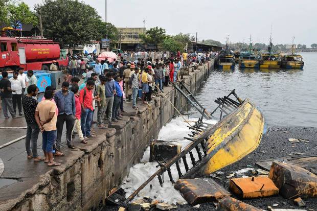 Locals at the site after firefighters extinguished the fire that broke out in a jetty area, in Visakhapatnam. (PTI Photo)