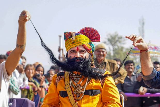 Foreign tourists with a participant of the 'longest moustache' competition during the annual Pushkar Fair, in Pushkar. (PTI Photo)