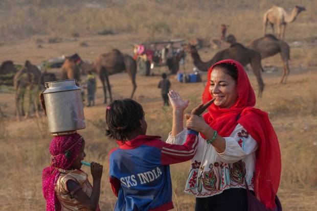 A foreign tourist interacts with children at the annual Pushkar Fair, in Pushkar. (PTI Photo)