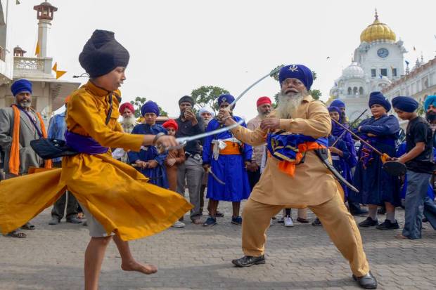 Sikh devotees perform 'Gatka', an ancient form of Sikh martial arts, during nagar procession ahead of the birth anniversary celebrations of Guru Nanak Dev, at the Golden Temple in Amritsar.. (PTI Photo)