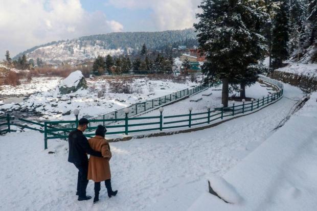 Tourists walk on a snow-covered road after a fresh snowfall in Tangmarg. (Photo: PTI)